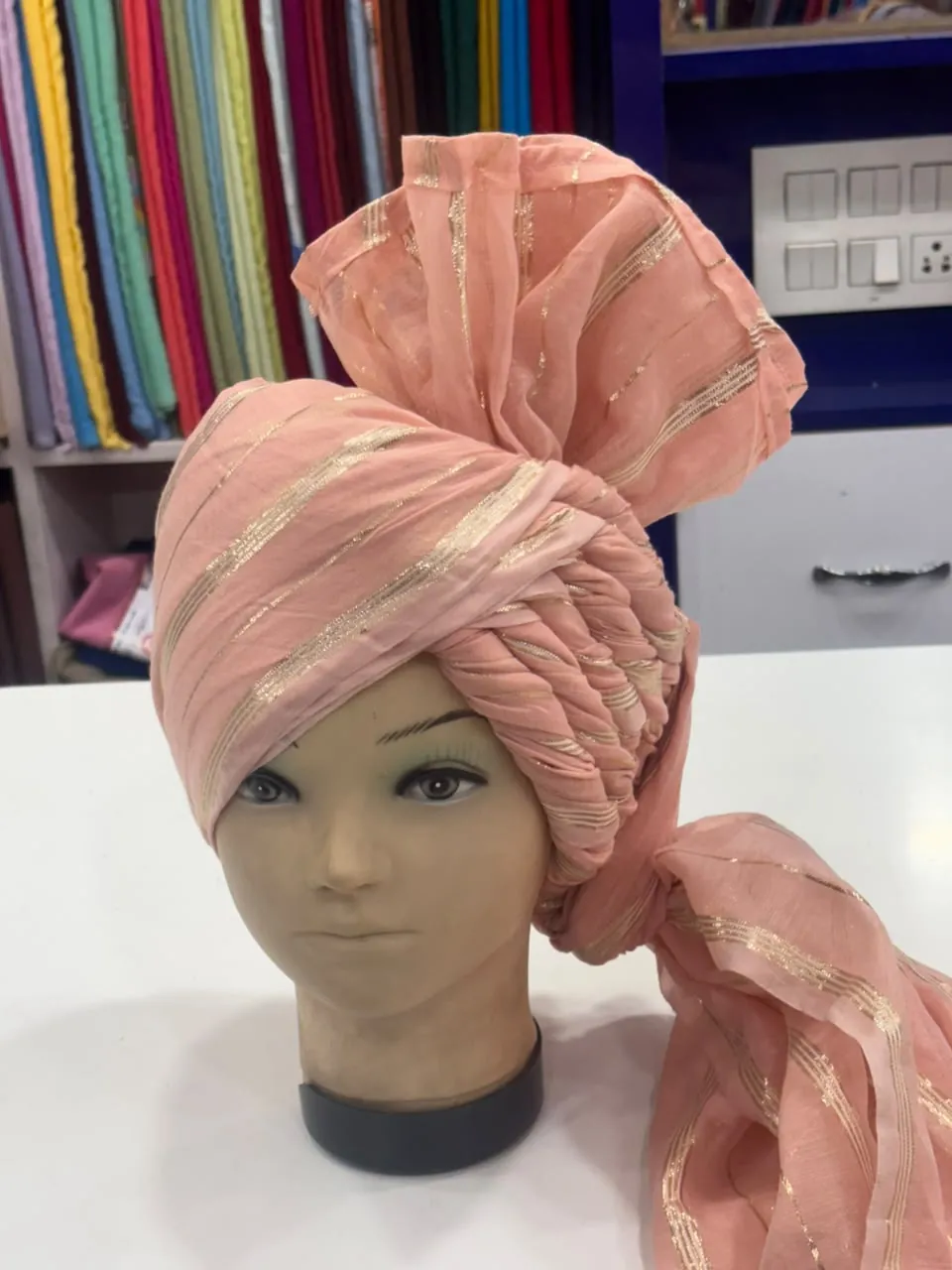 Original peach wedding pagri displayed on a mannequin inside the shop