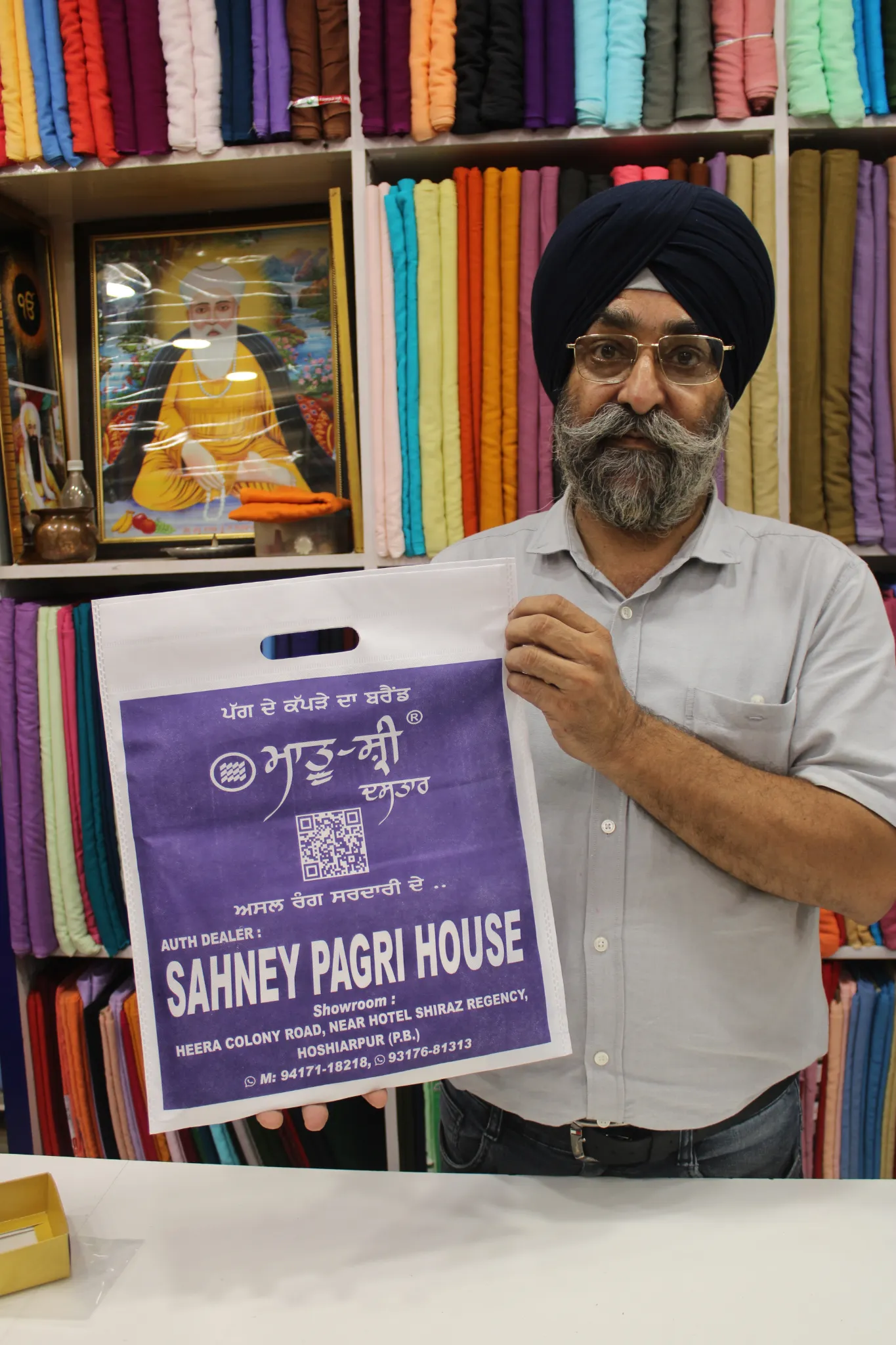 Owner holding a Sahney Pagri House bag inside the colourful showroom